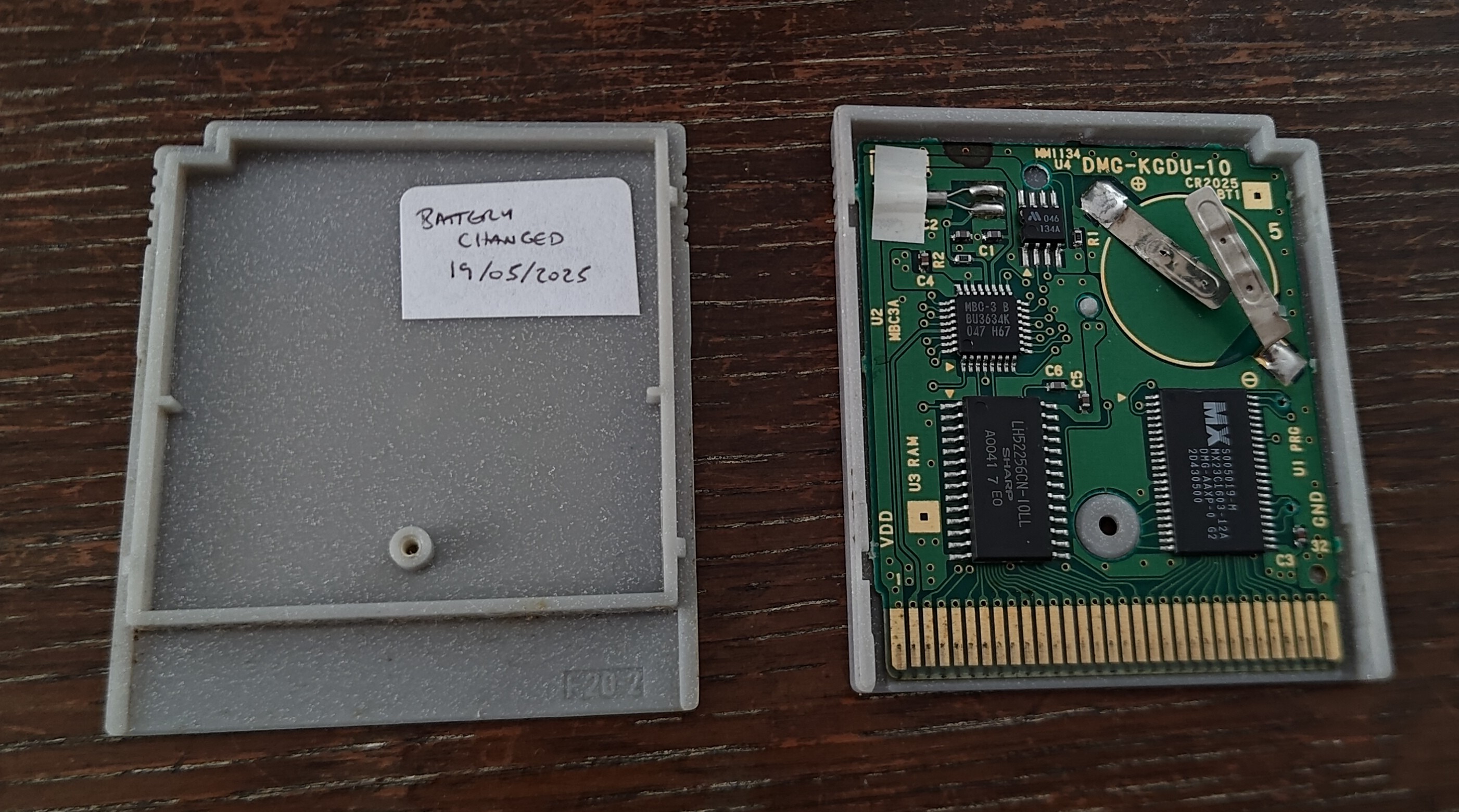 The open Pokémon Silver cartridge - the battery is gone leaving the two metal tab connectors and a white label on the case now reads 'BATTERY CHANGED 19/05/2025'