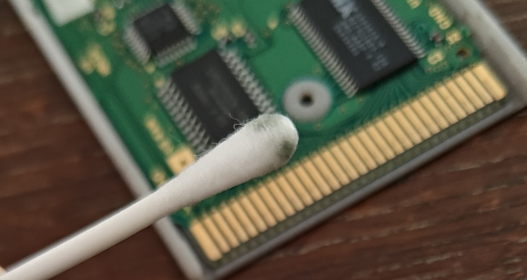 The cotton bud now covered in dark grey blotches while the out-of-focus connector looks much cleaner