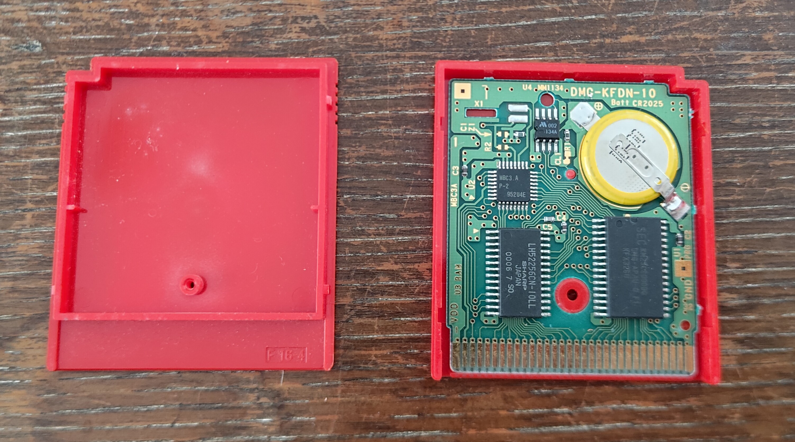 The open Pokémon Red cartridge - the original battery has a yellow edge and is soldered to the tabs